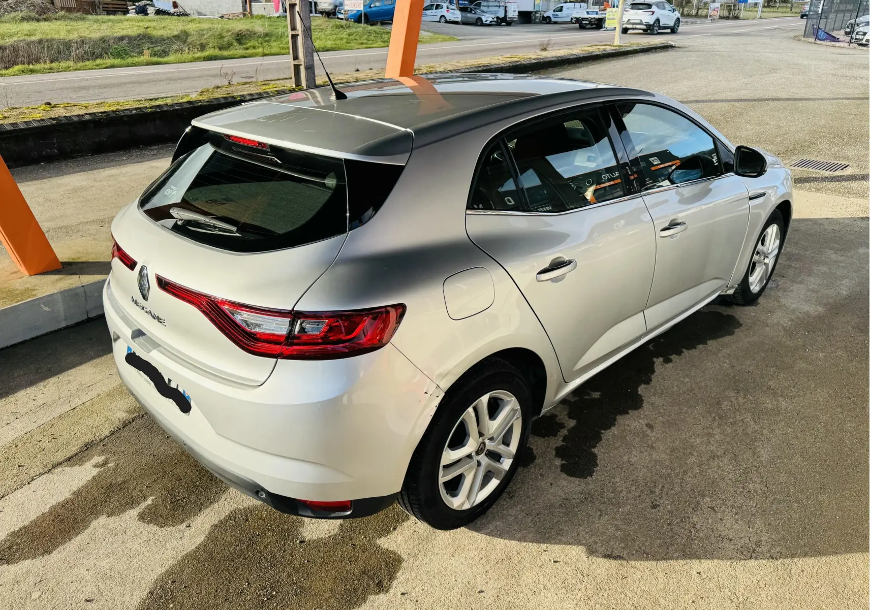 Renault Mégane IV berline gris vue 3/4 arrière droit, avec feux arrière LED et toit noir brillant.