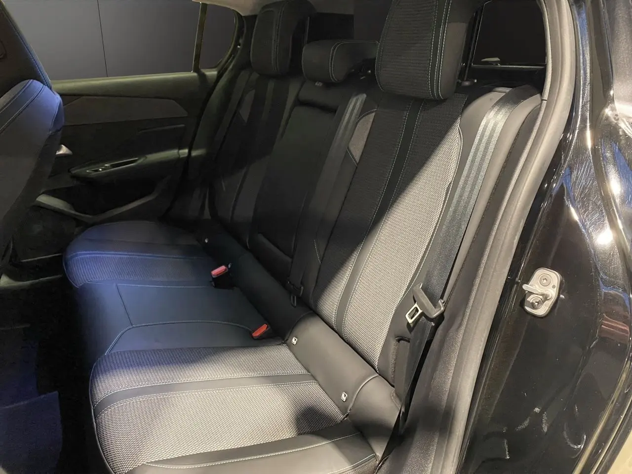 Vue intérieure côté droit des sièges arrière en tissu noir et cuir de la Peugeot 308 2024 noir Perla Nera.