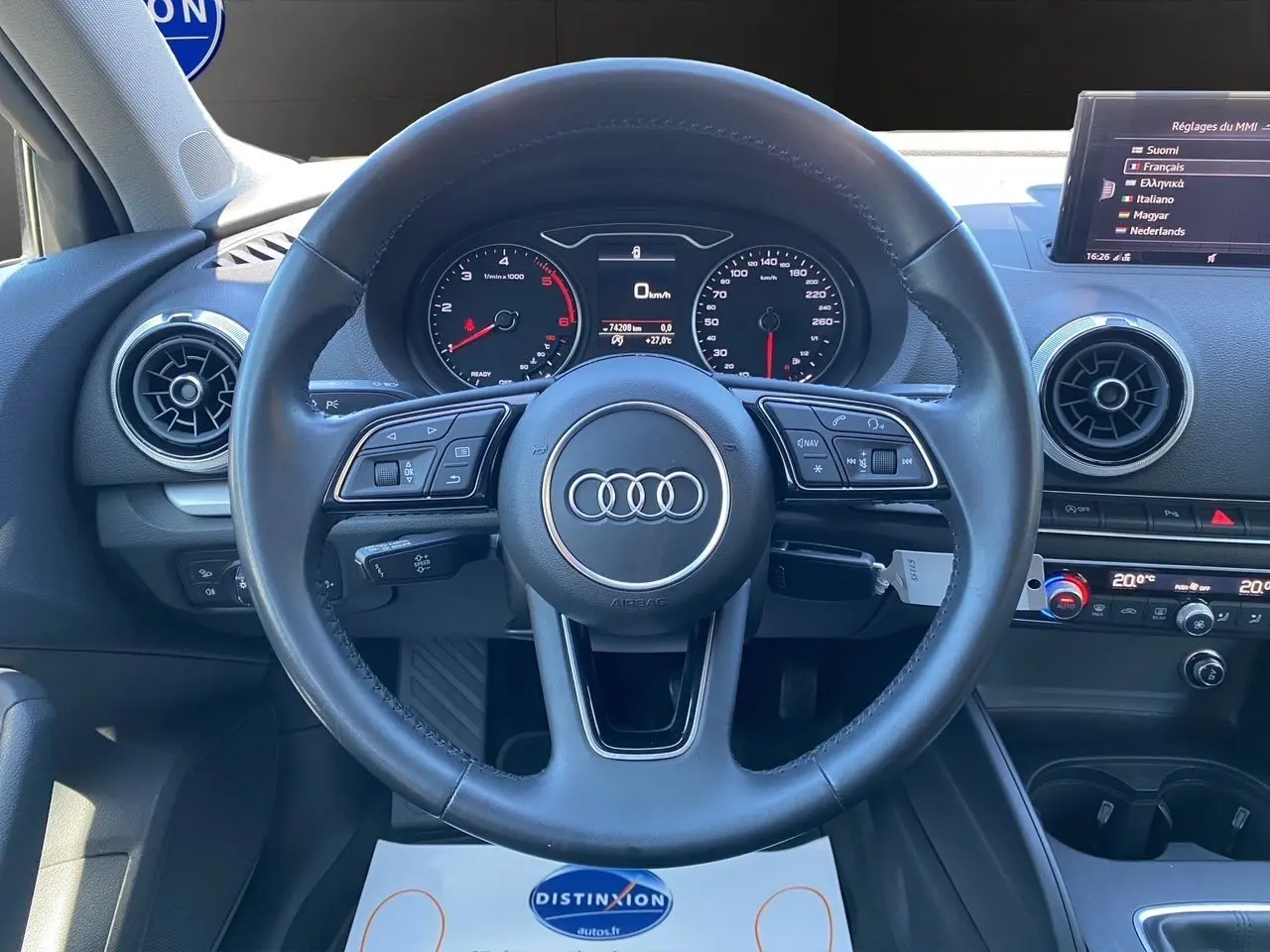 Vue centrée sur le volant cuir noir d'une Audi A3 Sportback 2020 avec tableau de bord et écran MMI en arrière-plan.