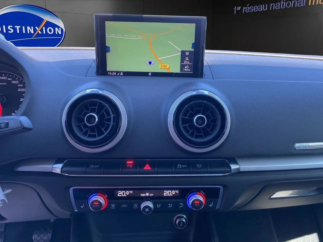 Tableau de bord de l'Audi A3 Sportback 2020 avec écran GPS, aérateurs ronds et commandes climatisation 2 zones visibles de face.