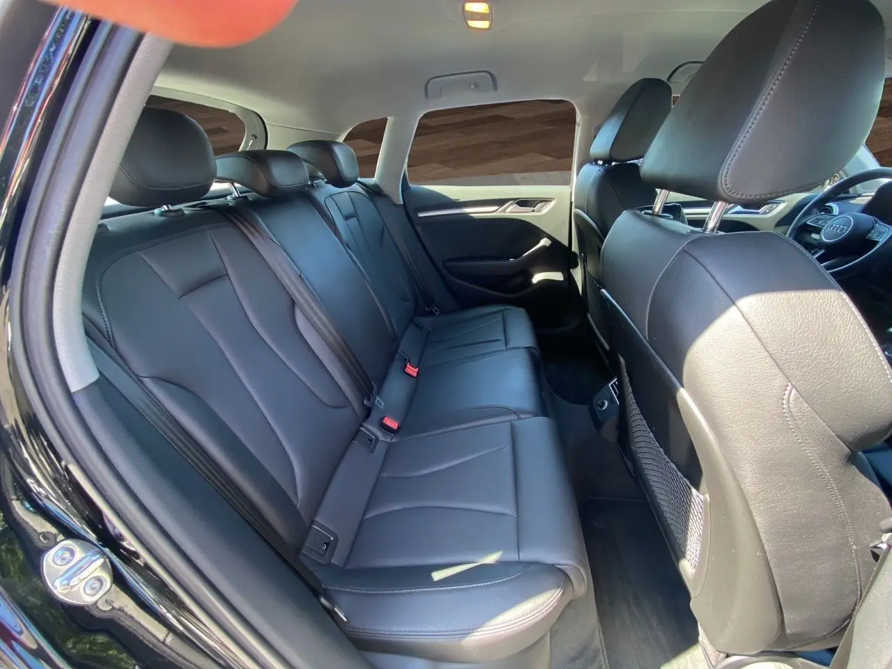 Vue intérieure côté gauche montrant la banquette arrière en cuir noir chauffant de l'Audi A3 Sportback 2020.