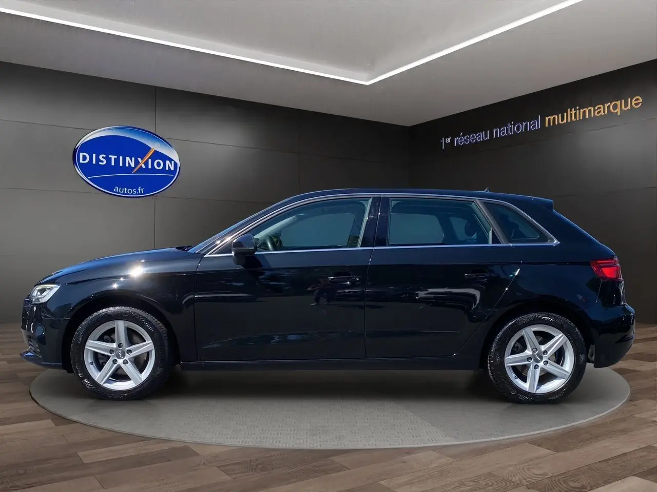 Profil côté gauche d'une Audi A3 Sportback noire 5 portes avec jantes alliage 5 branches en étoile.