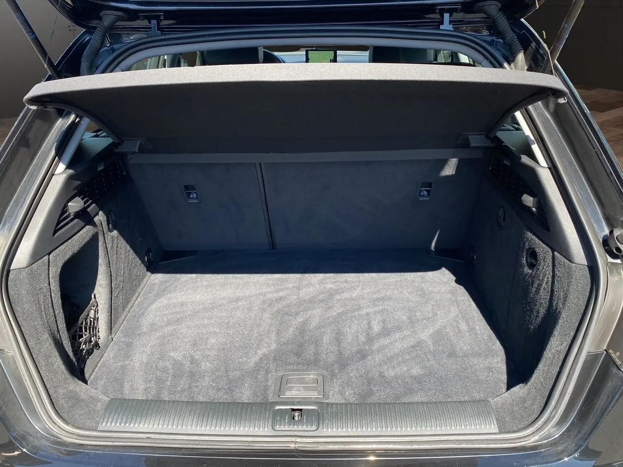 Coffre ouvert vu de l'arrière d'une Audi A3 Sportback noire, montrant un espace de chargement propre et spacieux.