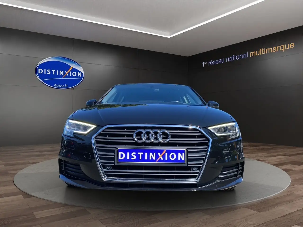 Vue frontale d'une Audi A3 Sportback noire 2020 avec phares LED et calandre chromée dans un showroom.