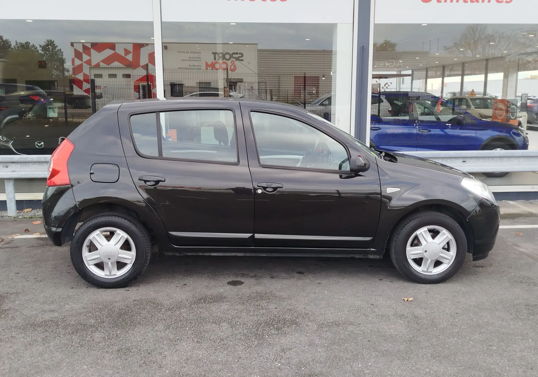 Profil côté gauche d'une Dacia Sandero noire de 2011, cinq portes, avec jantes alliage et rétroviseurs noirs.