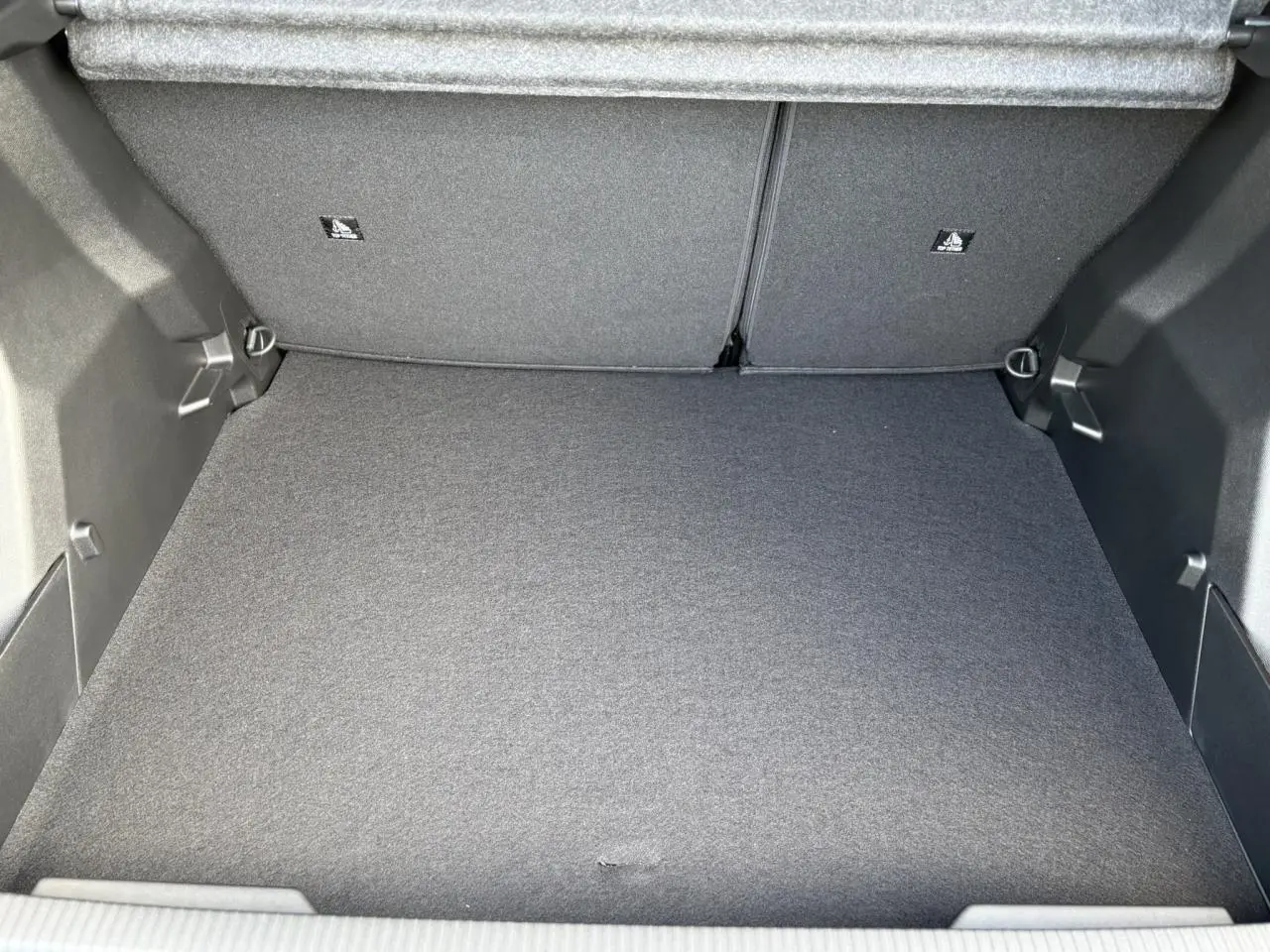 Vue intérieure du coffre spacieux et propre de la Peugeot 2008 Hybrid 145 e-DSC6 Allure, revêtement gris foncé.