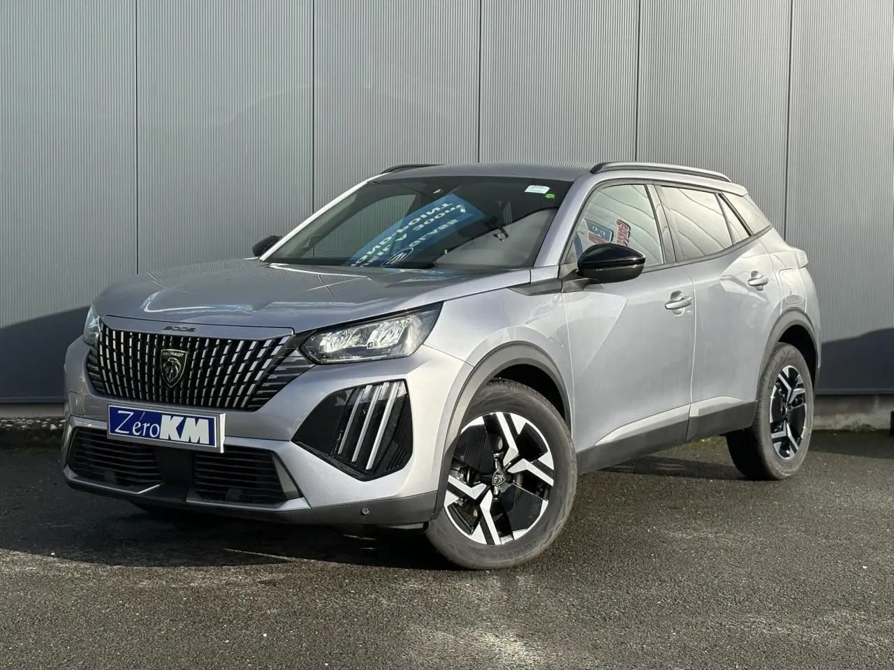 Peugeot 2008 Hybrid 145 e-DSC6 Allure gris Artense, vue 3/4 avant avec calandre noire et jantes bi-ton 17 pouces.