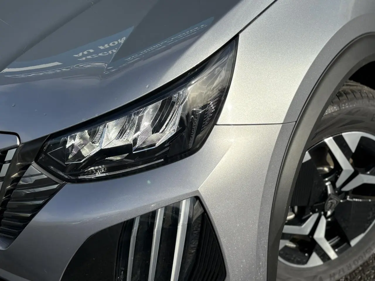 Gros plan sur l'avant droit gris Artense du Peugeot 2008 Hybrid 145 avec phare LED et jante alliage 17'' bi-ton.
