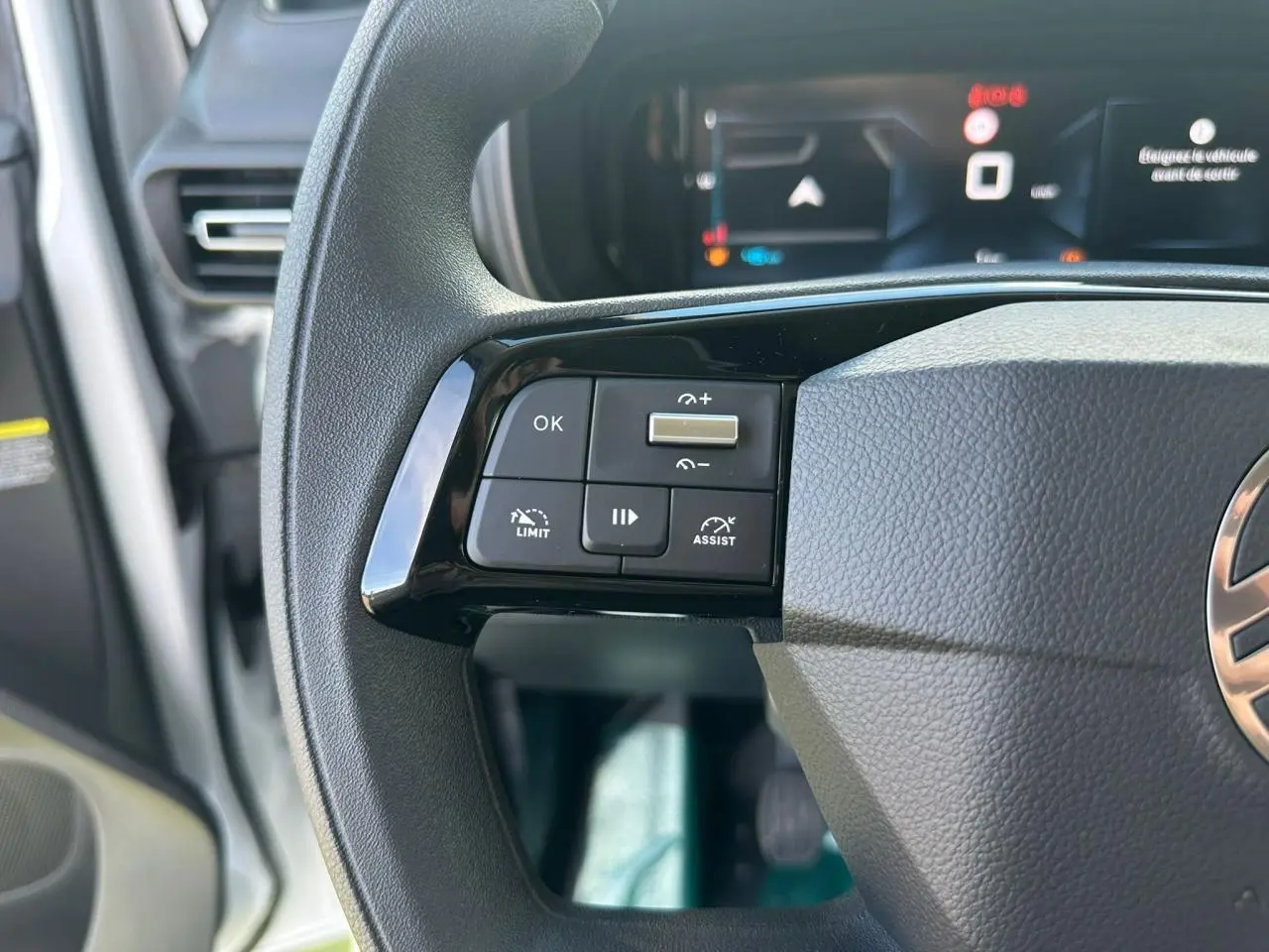 Gros plan sur les commandes gauche du volant noir du Citroën Berlingo 2026 avec affichage numérique en arrière-plan.