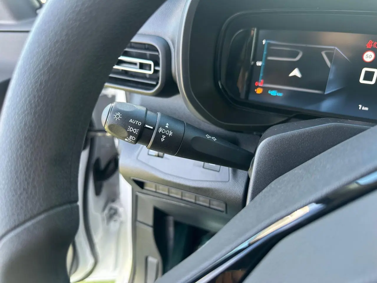 Gros plan sur la commande des feux et clignotants à gauche du volant dans l’habitacle du Citroën Berlingo blanc Icy.