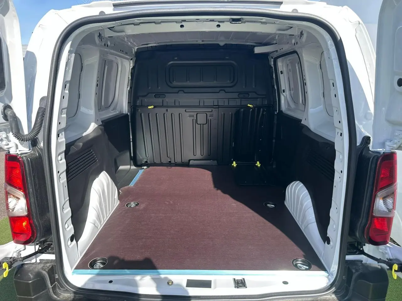 Vue arrière du Citroën Berlingo blanc Icy avec porte ouverte montrant la zone de chargement avec plancher bois antidérapant.