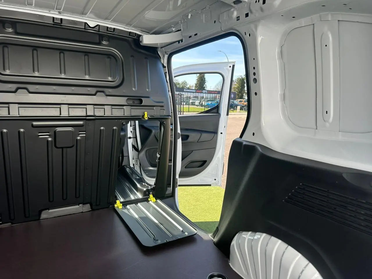 Vue intérieure du coffre du Citroën Berlingo blanc Icy avec porte latérale droite ouverte et cloison partielle rabattue.