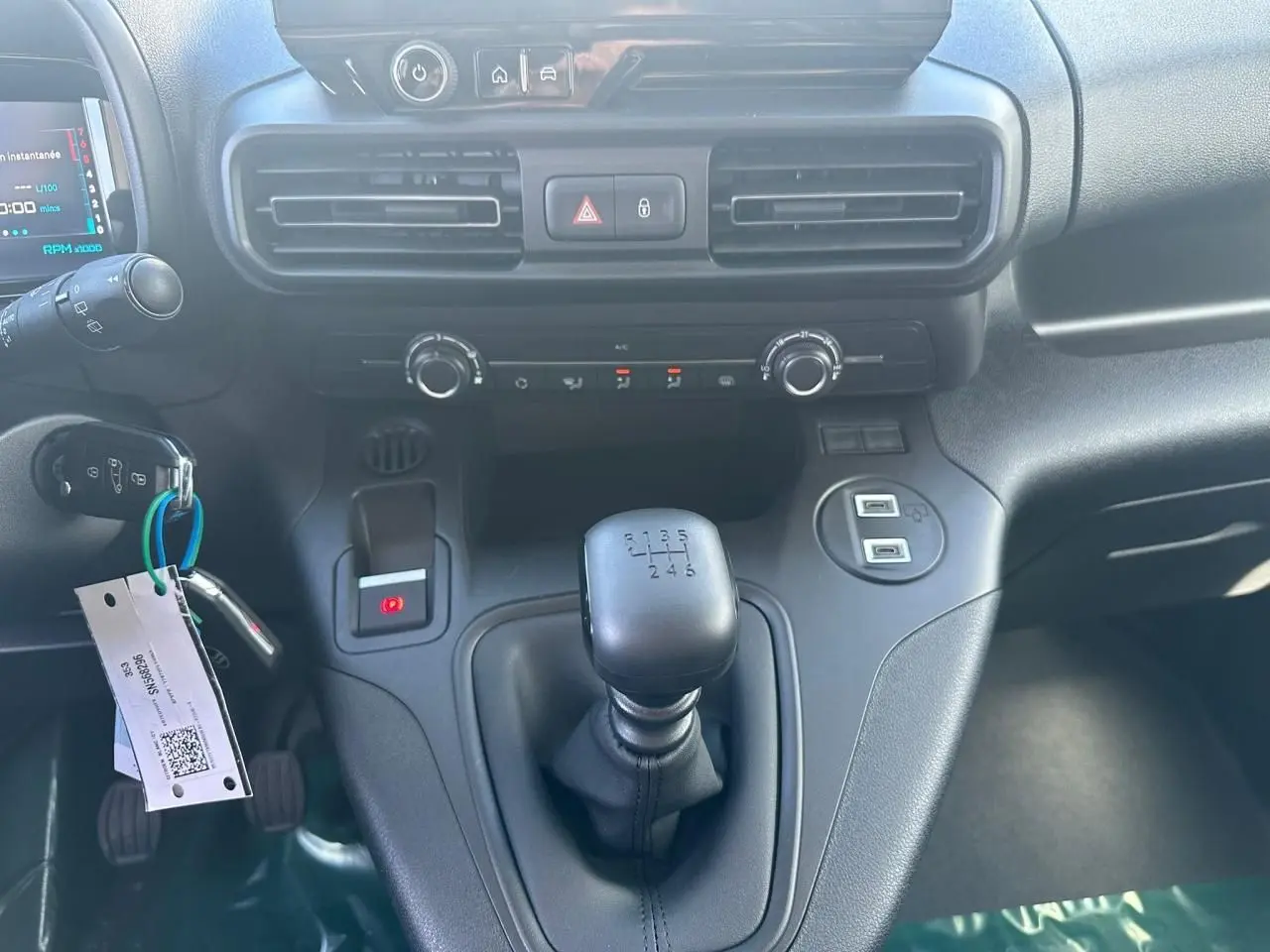 Vue rapprochée de la console centrale du Citroën Berlingo blanc, avec levier de vitesses manuel et commandes climatisation.