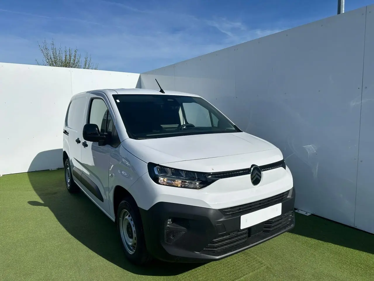 Vue 3/4 avant droite d’un Citroën Berlingo blanc Icy avec pare-chocs noir mat et jantes tôles grises.