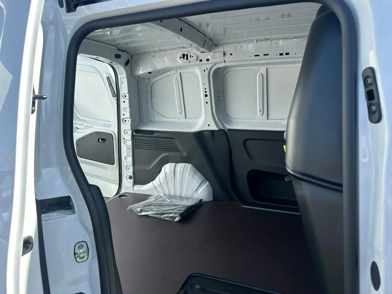 Vue intérieure de la zone de chargement arrière du Citroën Berlingo blanc Icy, avec plancher bois antidérapant et cloison fixe.