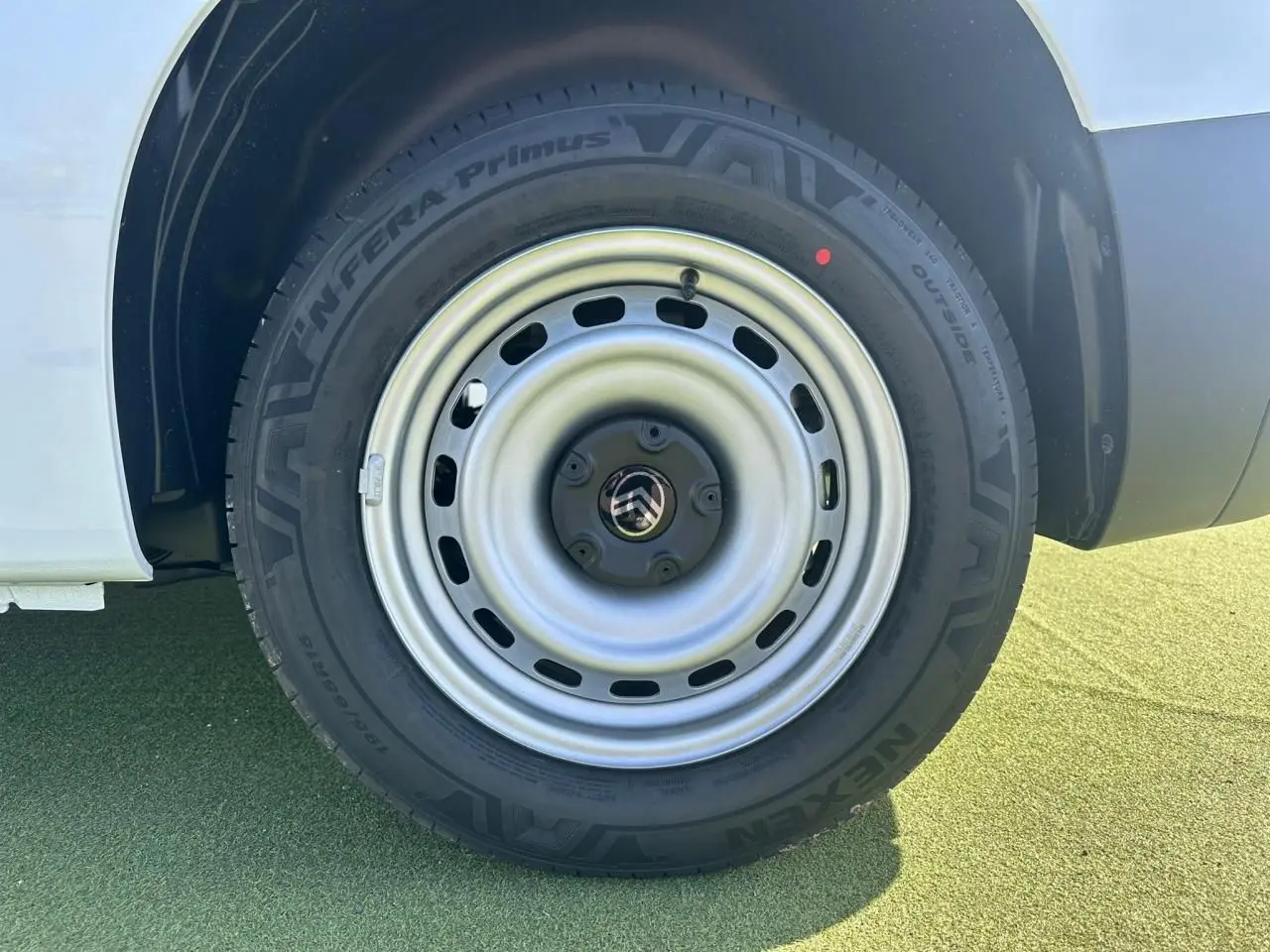 Gros plan sur la roue arrière droite du Citroën Berlingo blanc Icy avec jante tôle grise et logo Citroën au centre.