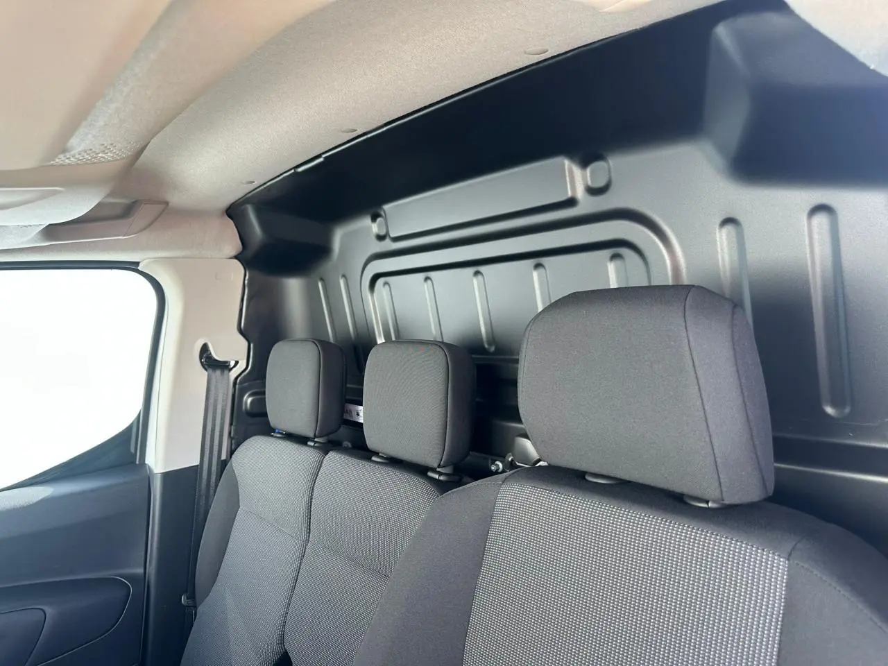 Vue intérieure côté droit montrant les sièges avant noirs et la cloison métallique du Citroën Berlingo III Van Blanc Icy.