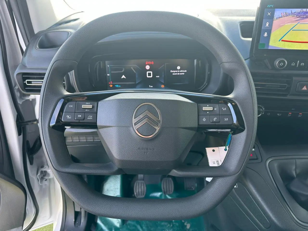 Vue intérieure centrée sur le volant noir du Citroën Berlingo blanc Icy avec tableau de bord numérique et écran tactile.