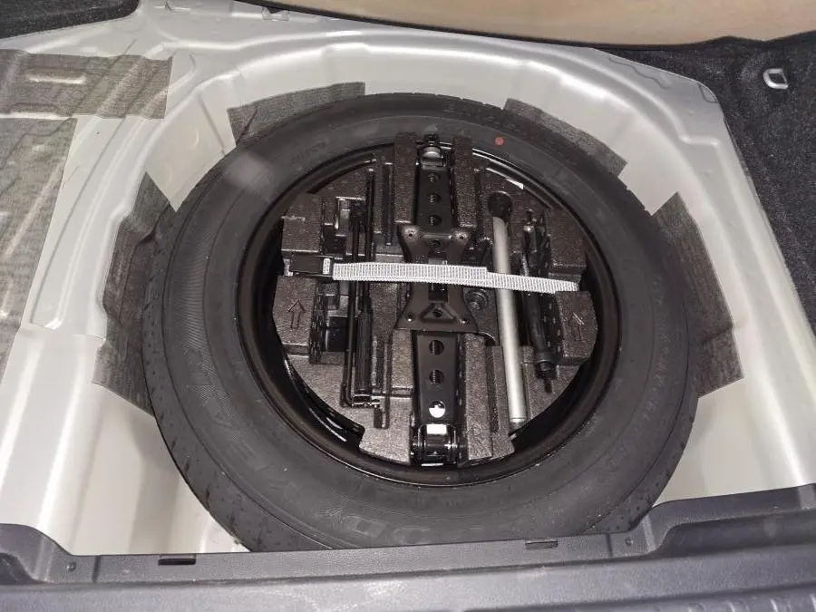 Vue plongeante sur la roue de secours et les outils de bord dans le coffre d'une Skoda Kamiq gris 2023.