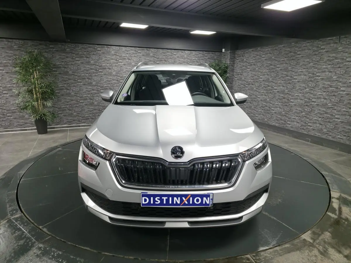 Vue avant d'un Skoda Kamiq gris métallisé 2023, avec calandre noire et feux LED distinctifs, en showroom.