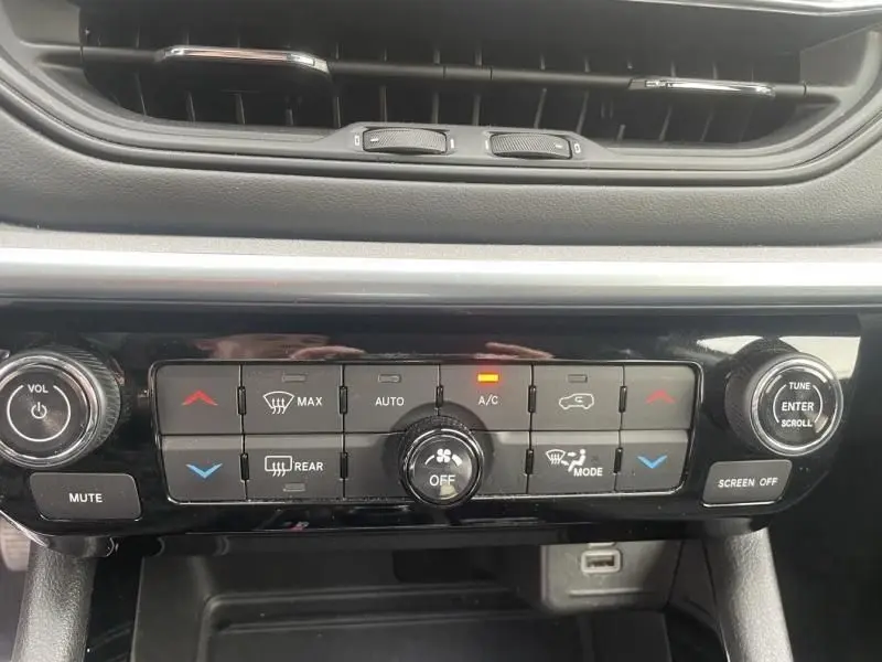 Vue rapprochée du tableau de bord du Jeep Compass 2023 blanc, montrant les commandes de climatisation et audio.
