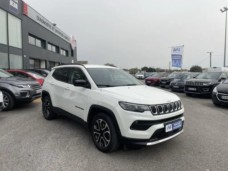 Jeep Compass blanc vue 3/4 avant droit, calandre distinctive à sept fentes et jantes noires bicolores.