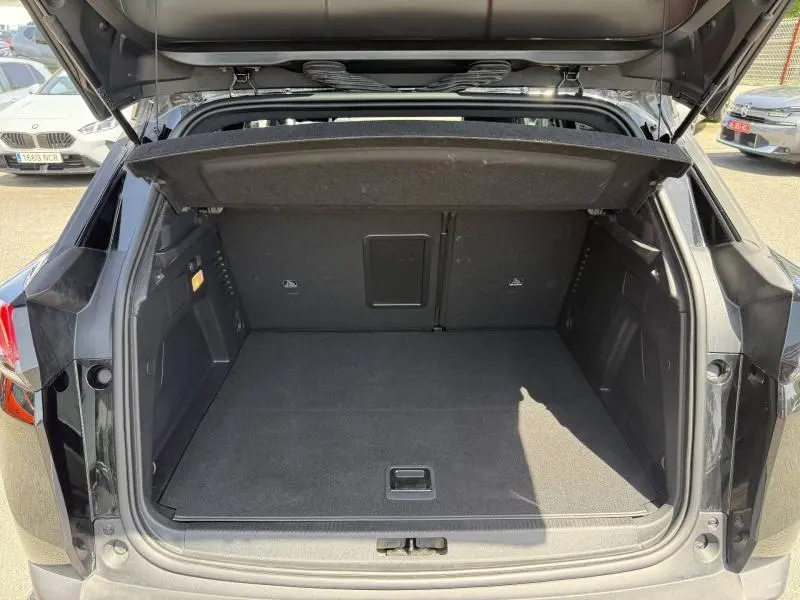 Coffre ouvert vu de l'arrière d'un Peugeot 3008 noir Perla Nera avec plancher plat et cache-bagages relevé.
