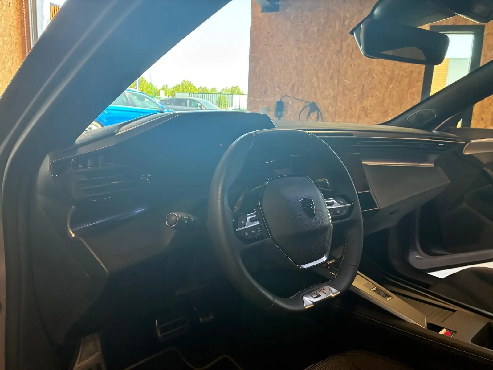 Vue intérieure côté conducteur de la Peugeot 308 gris 1.2 Hybrid 136 E-DCS6 GT avec volant multifonction et tableau de bord moderne.