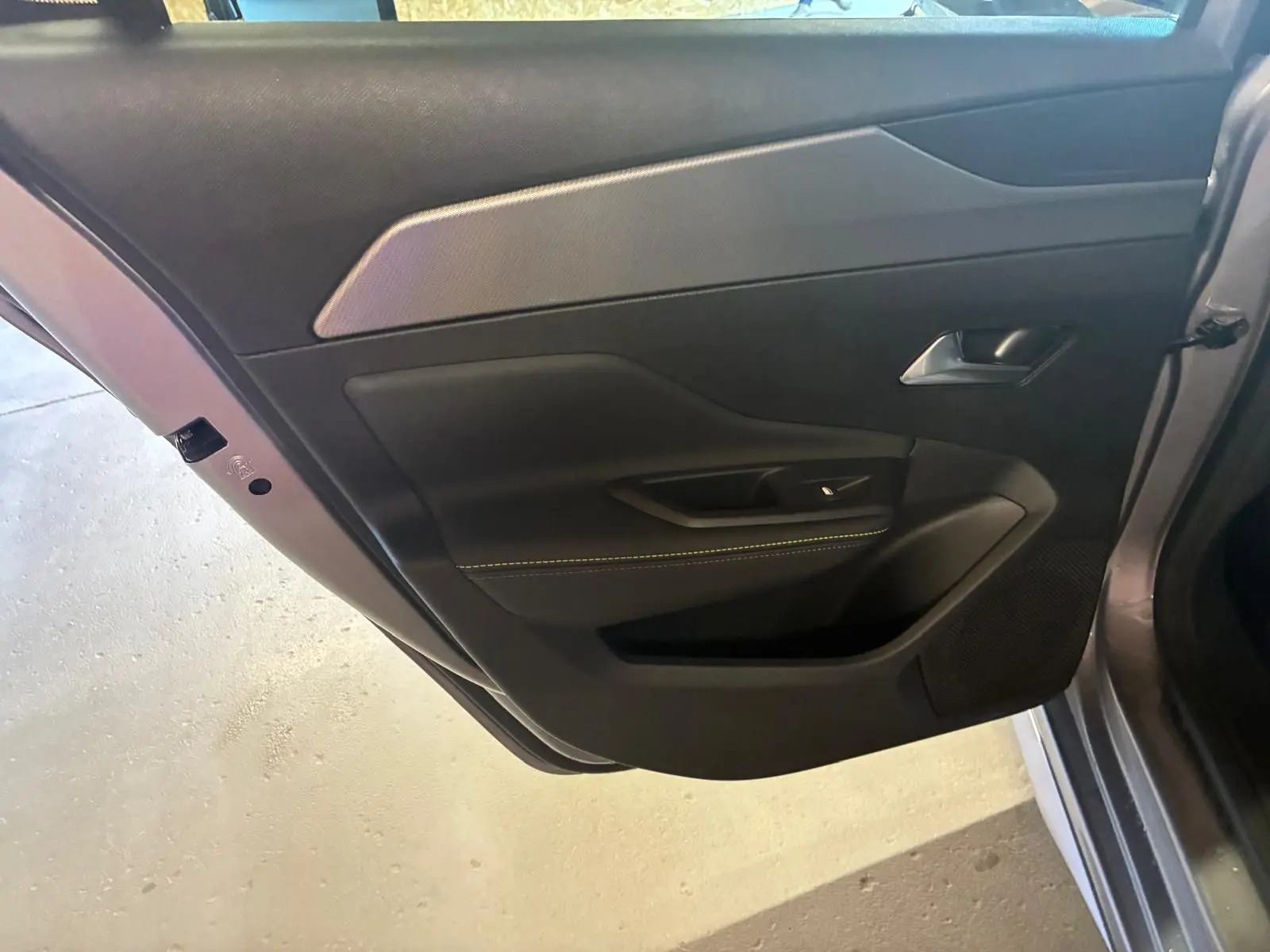 Vue rapprochée de la porte arrière gauche gris foncé de la Peugeot 308 1.2 Hybrid 2025 avec garniture noire et poignée argentée.