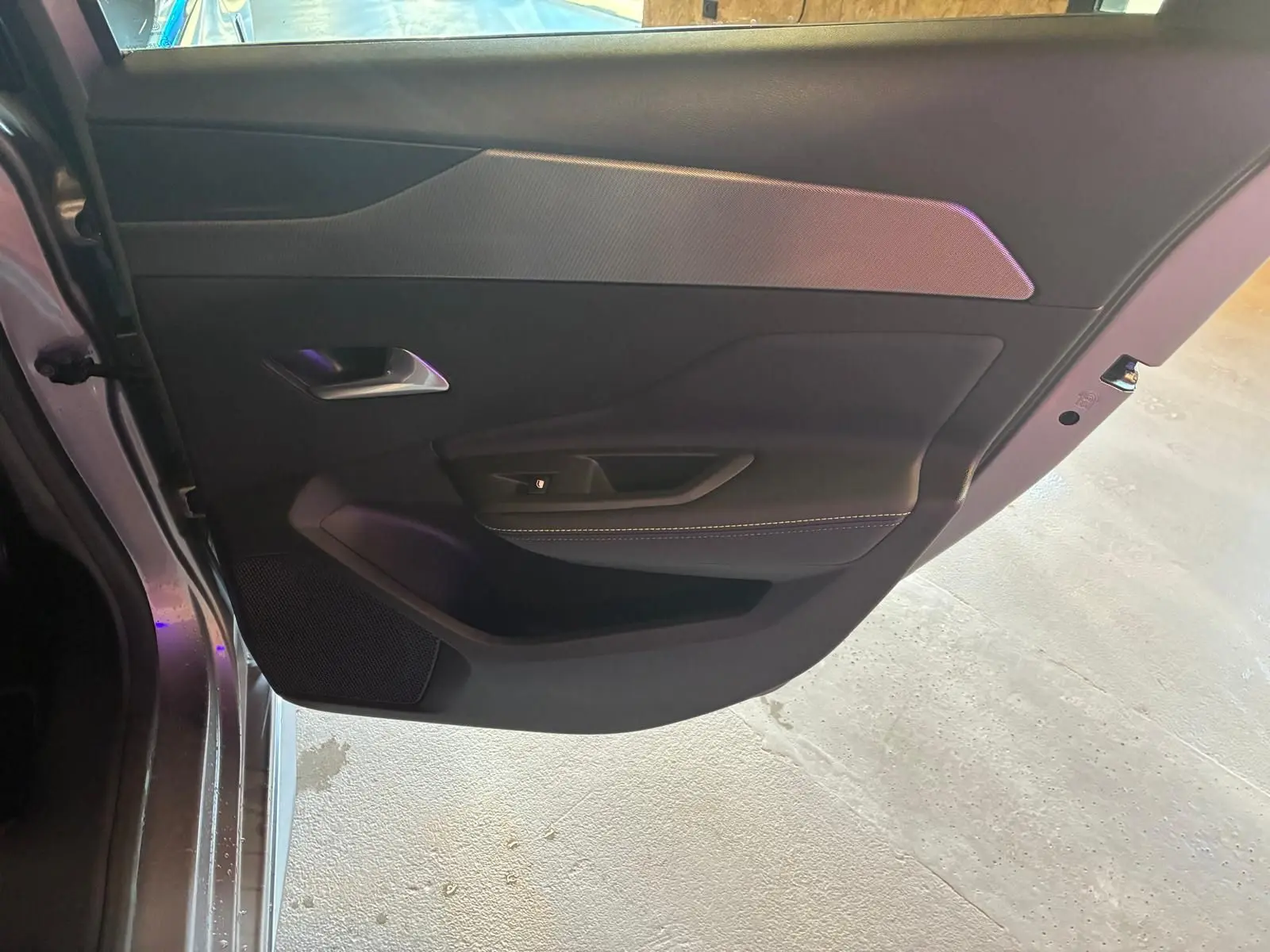 Vue intérieure de la porte arrière gauche gris foncé de la Peugeot 308 1.2 Hybrid 136 GT avec garniture textile et poignée argentée.