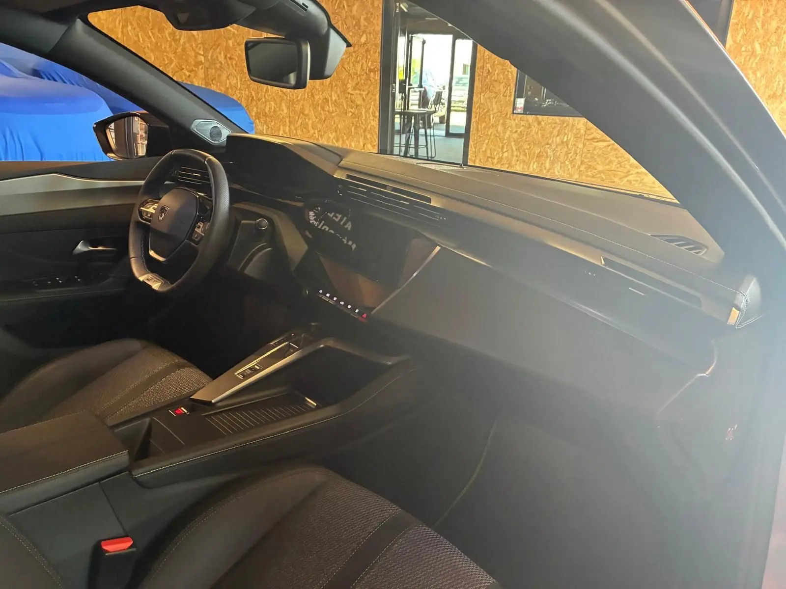 Vue intérieure côté conducteur de la Peugeot 308 gris 1.2 Hybrid 136 GT, avec tableau de bord moderne et volant compact.