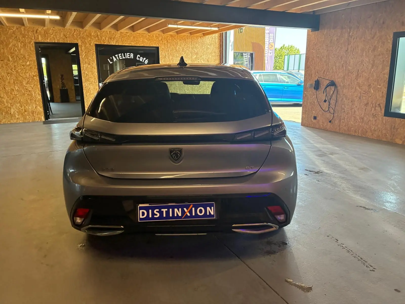 Vue arrière d'une Peugeot 308 gris métallisé 2025 GT, avec feux LED et double sortie d'échappement visible en intérieur.