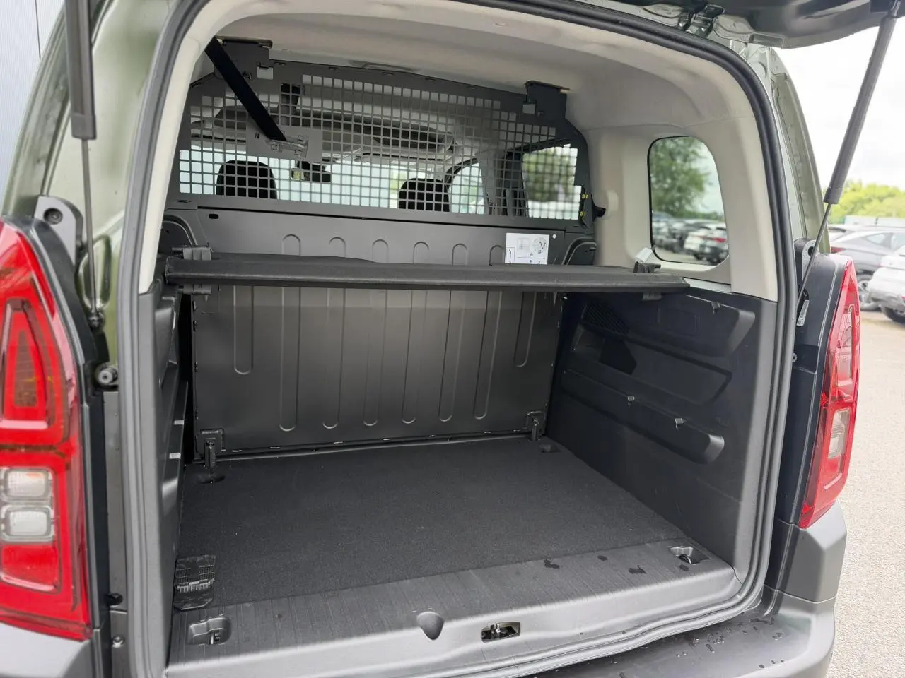 Coffre ouvert vu de l’arrière d’un Citroën Berlingo Multispace vert Sirkka avec cloison de séparation et lunette arrière ouvrante.