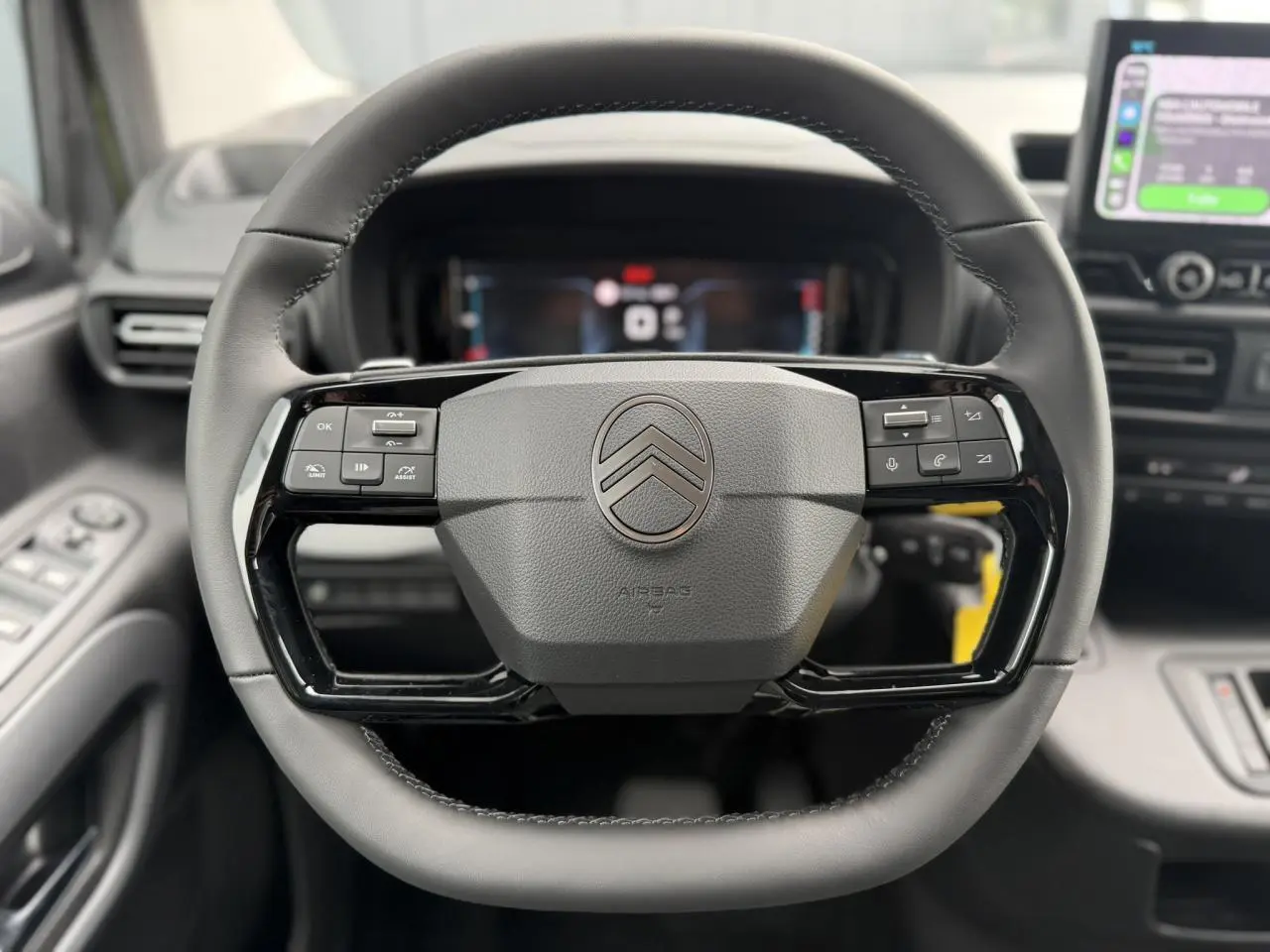 Vue rapprochée du volant cuir multifonctions de la Citroën Berlingo Multispace 2026 avec tableau de bord numérique en arrière-plan.