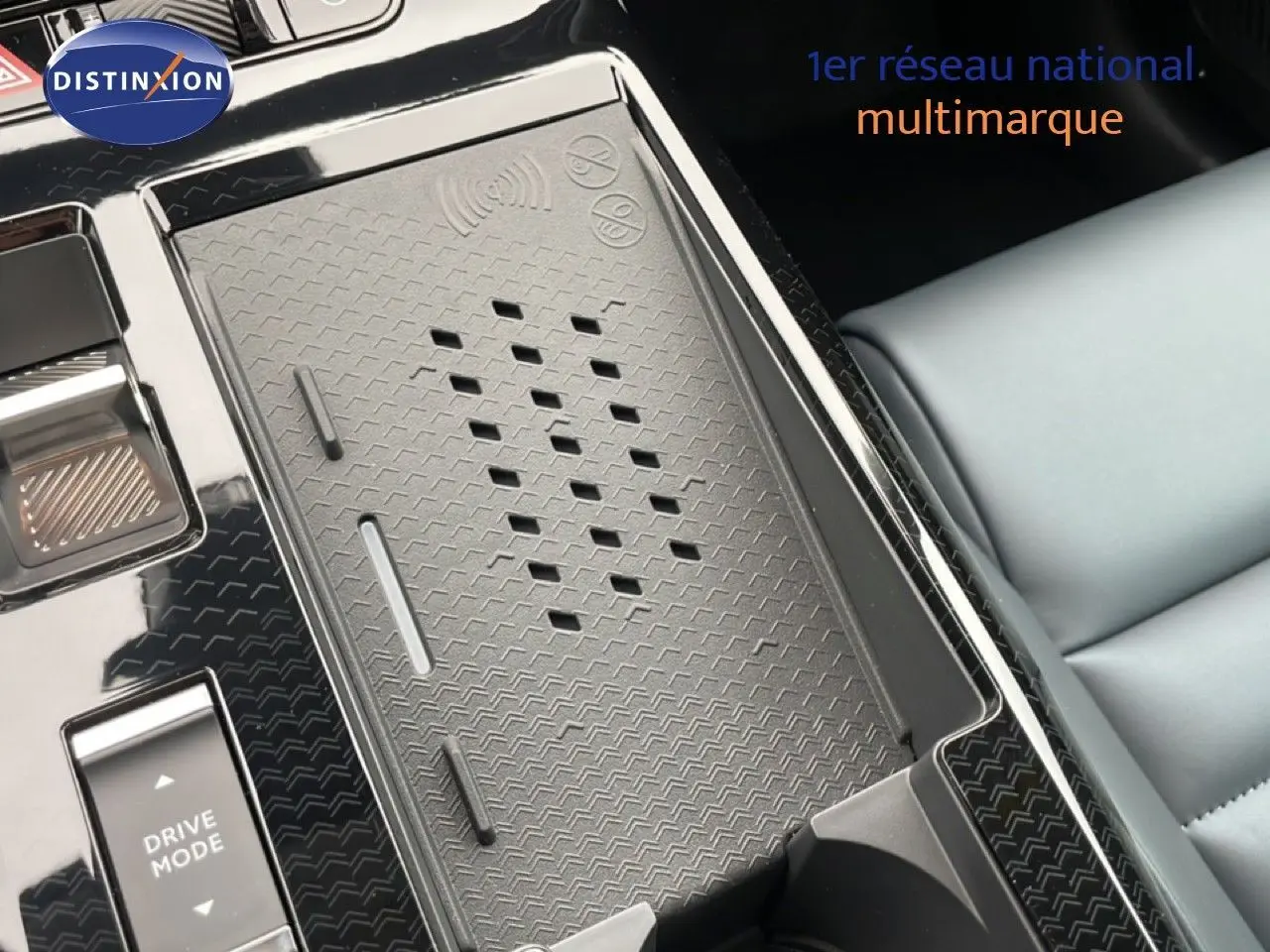 Détail de la console centrale du Citroën C5 Aircross Hybrid, montrant le chargeur sans fil et le bouton Drive Mode, avec siège gris clair visible.