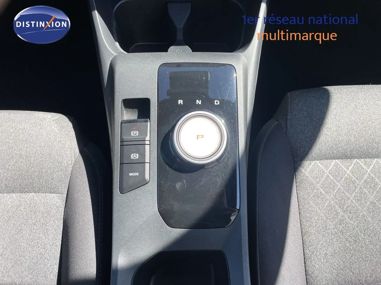Vue plongeante sur la console centrale du MG3 2025, avec molette de boîte auto et sièges tissu gris foncé.