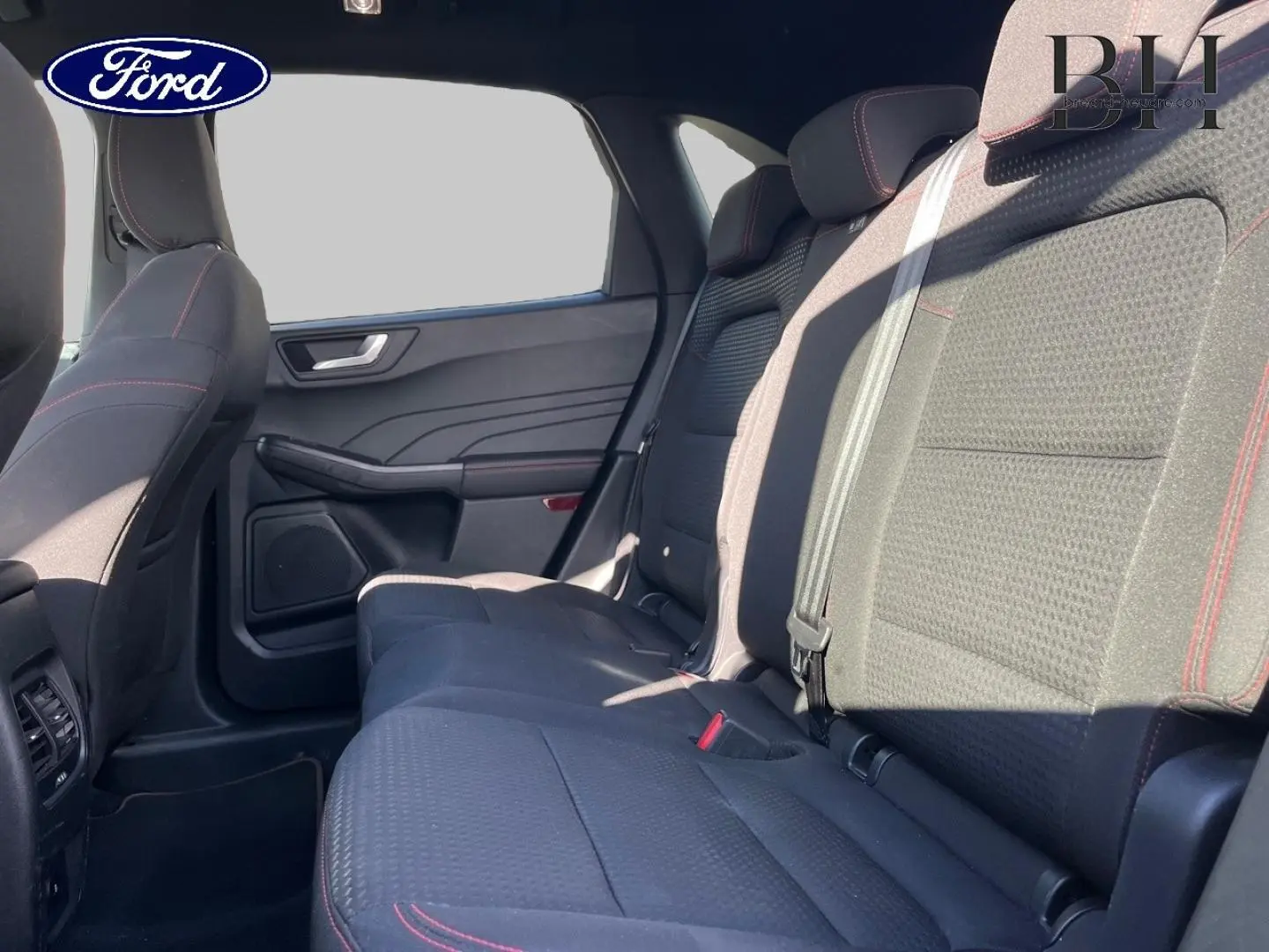 Vue intérieure côté droit sur la banquette arrière noire avec surpiqûres rouges du Ford Kuga 2023 finition ST-Line Business.