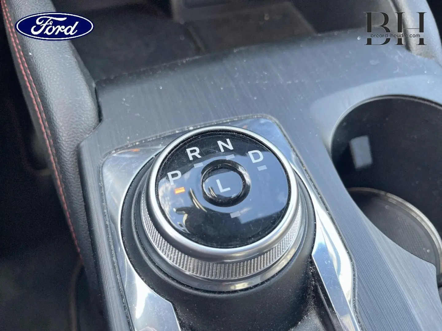 Gros plan sur la molette de boîte automatique du Ford Kuga noir Agate Métallisée, avec console centrale et porte-gobelets visibles.