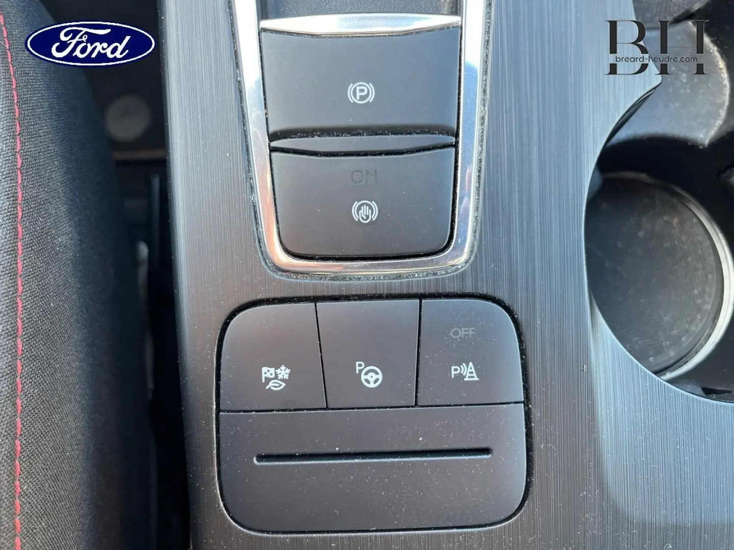 Vue rapprochée du panneau de commandes central noir et argenté avec boutons d’aide à la conduite dans un Ford Kuga noir.