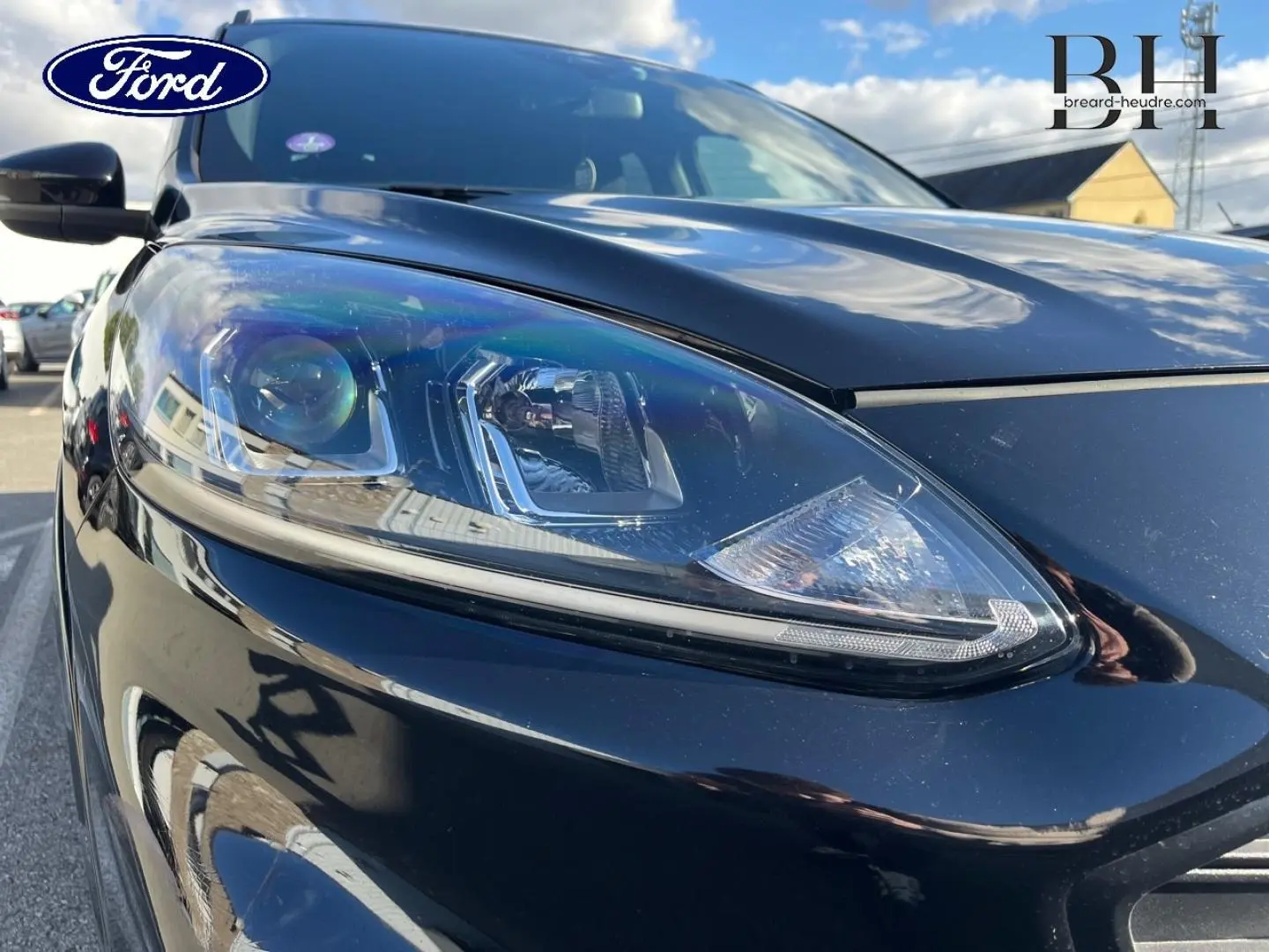 Gros plan sur le phare avant gauche du Ford Kuga noir Agate Métallisée, mettant en valeur son design moderne et précis.