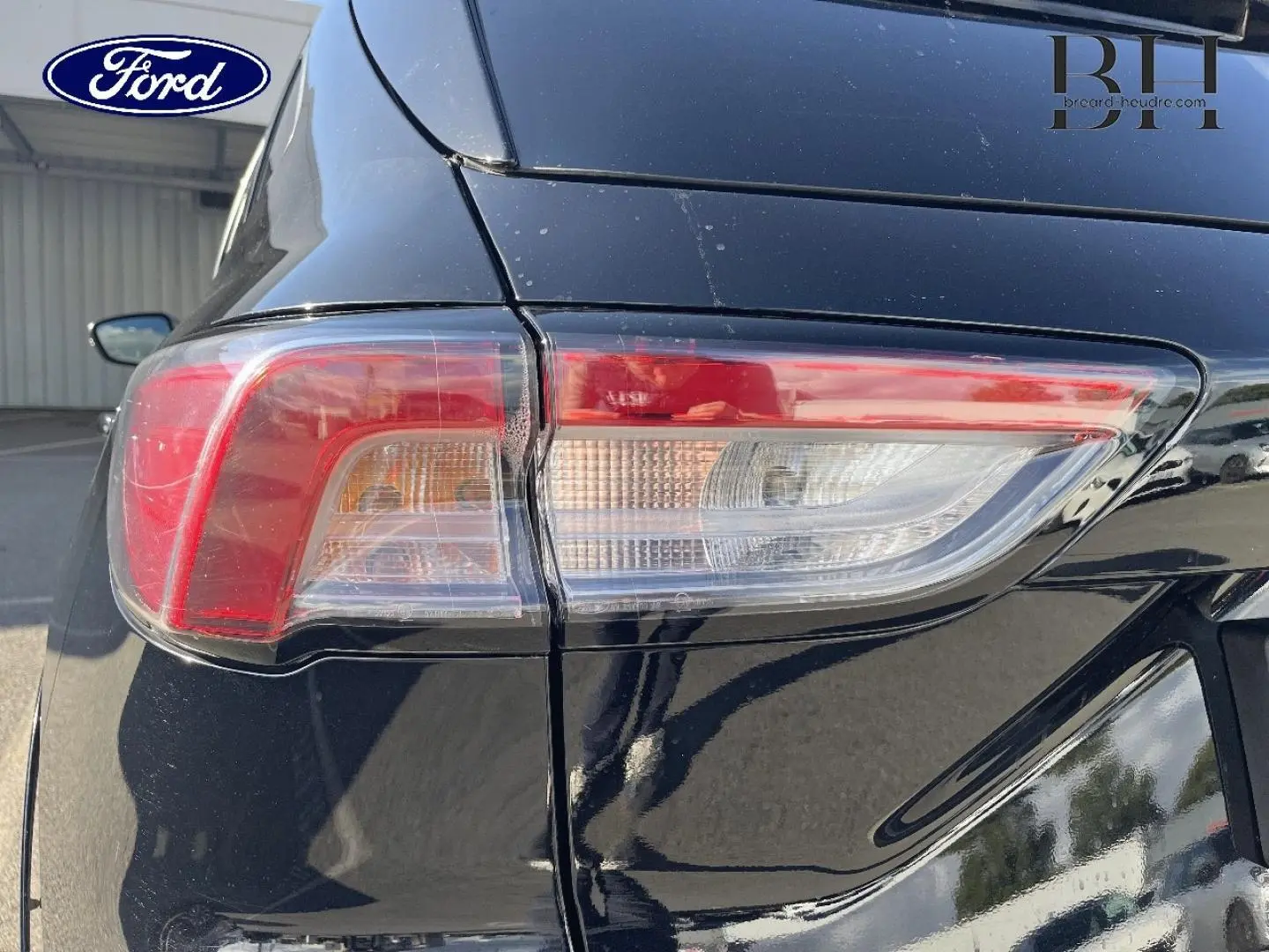 Gros plan sur le feu arrière droit d’un Ford Kuga noir Agate Métallisée 2023, avec reflet sur la carrosserie.