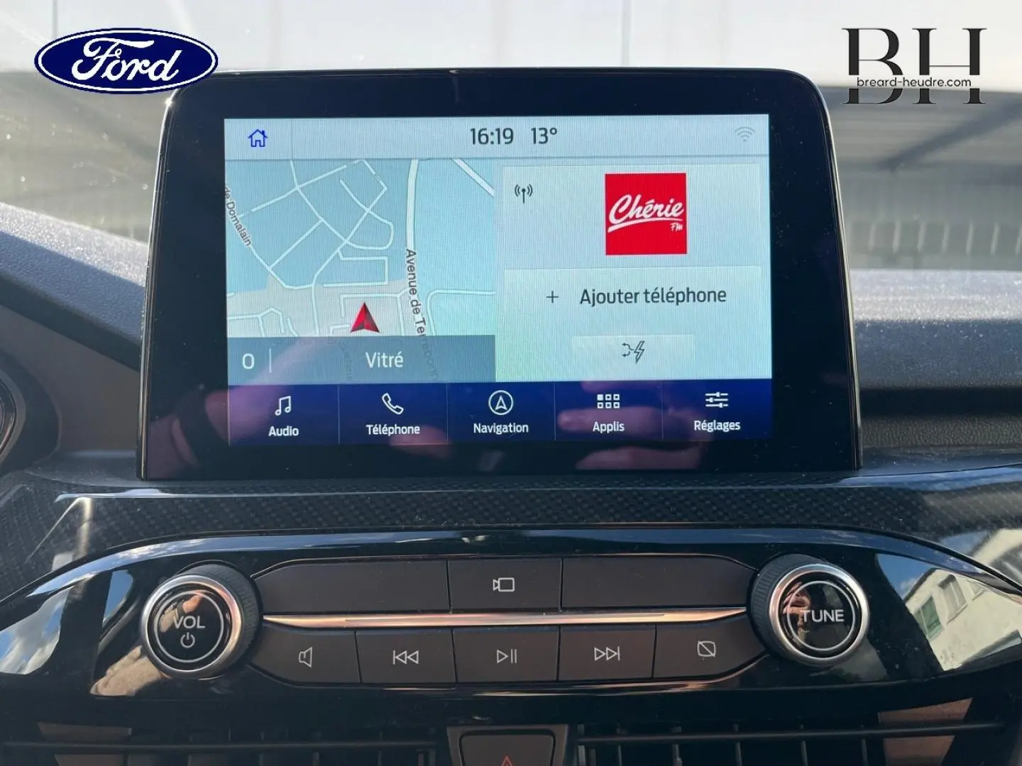 Écran tactile central du Ford Kuga 2023 avec interface navigation et commandes audio, vue intérieure frontale.