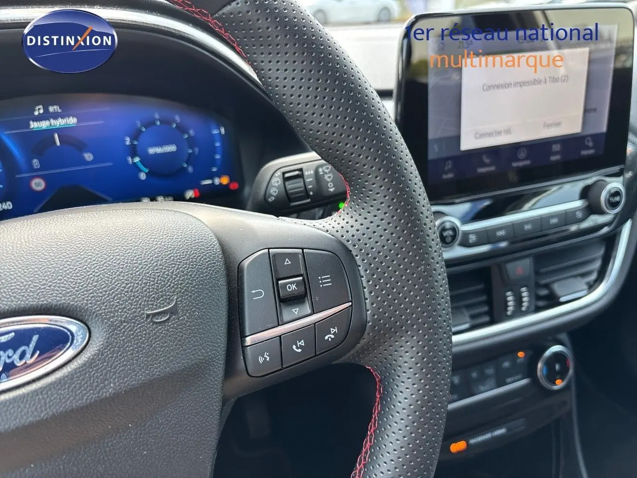 Vue rapprochée du volant perforé avec commandes intégrées et tableau de bord numérique du Ford Puma blanc 2022.