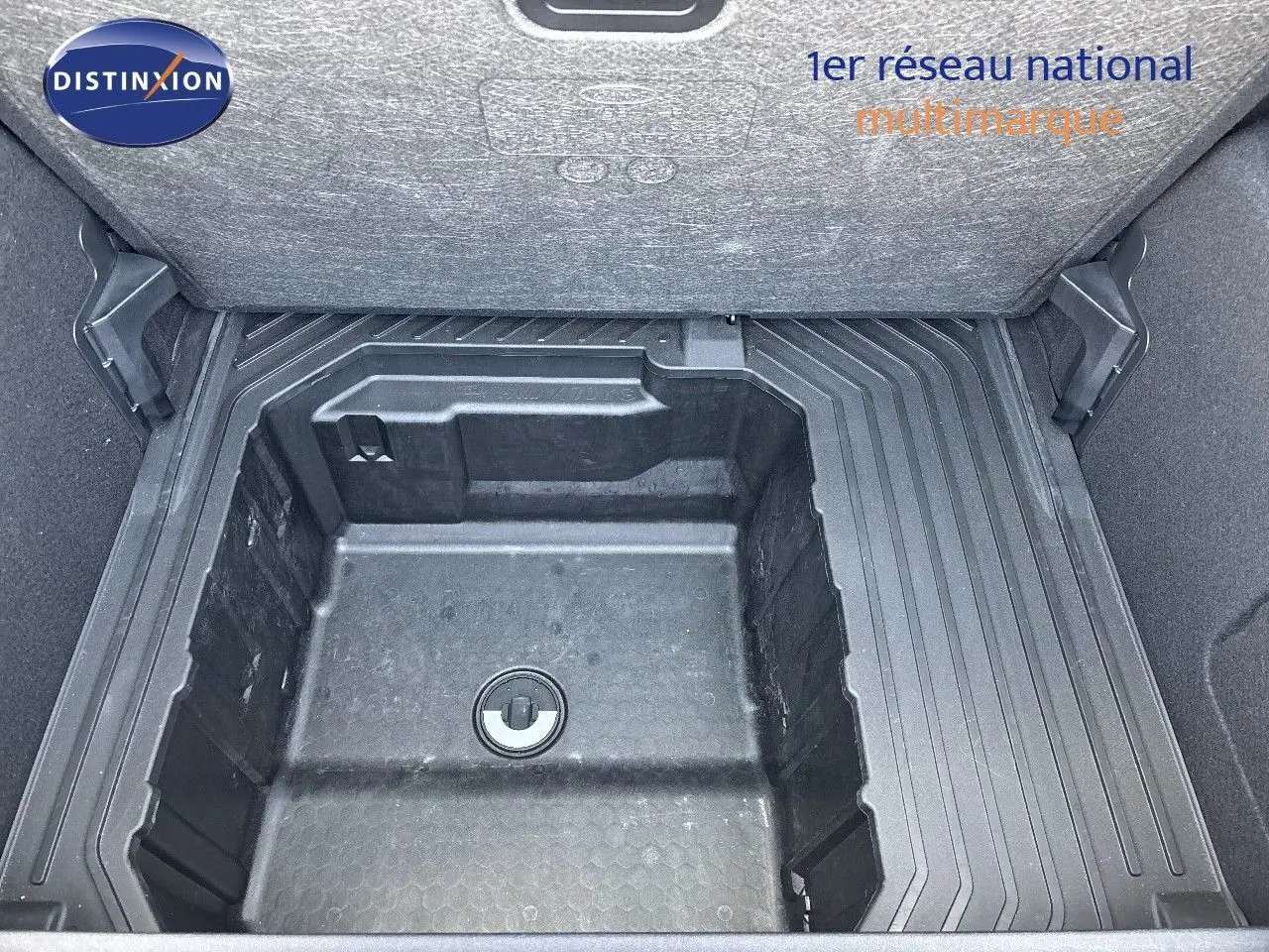 Coffre ouvert montrant le rangement sous plancher en plastique noir du Ford Puma blanc 2022, version hybride essence.