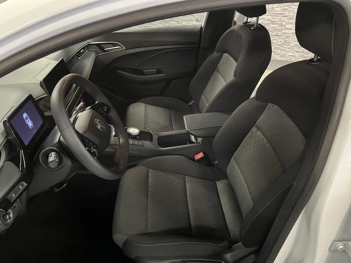 Vue intérieure côté conducteur de la MG3 1.5 Hybrid+ 195 Comfort 2024 avec sièges tissu noir et écran tactile central.
