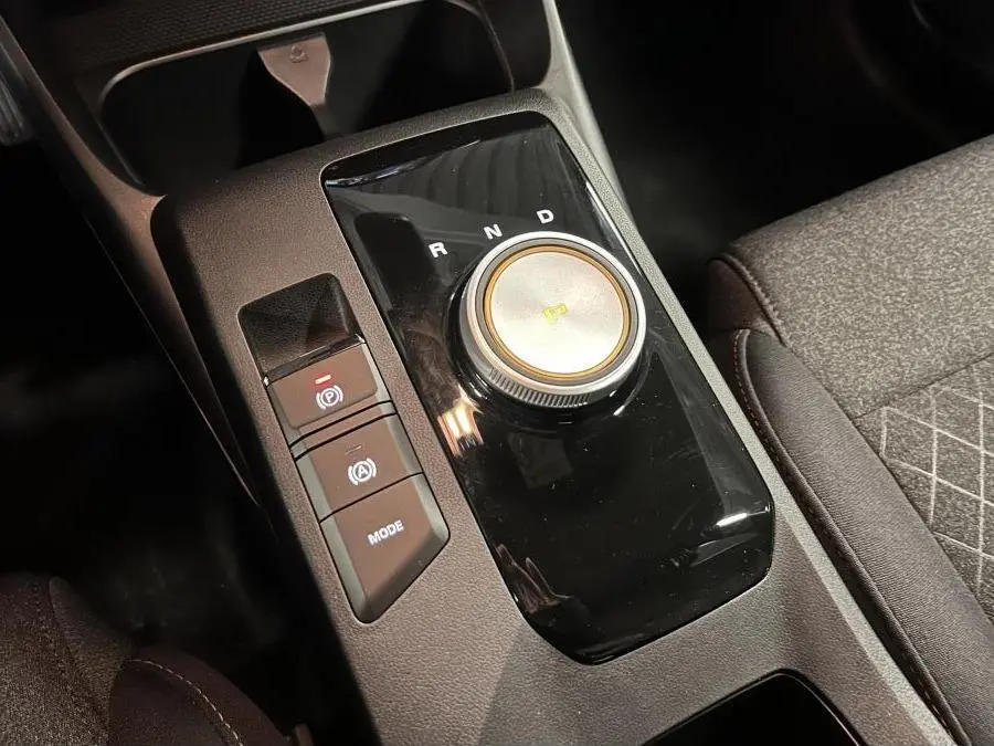 Gros plan sur la console centrale noire de la MG3 1.5 Hybrid+ 195 Comfort avec sélecteur rotatif de boîte auto et boutons de contrôle.