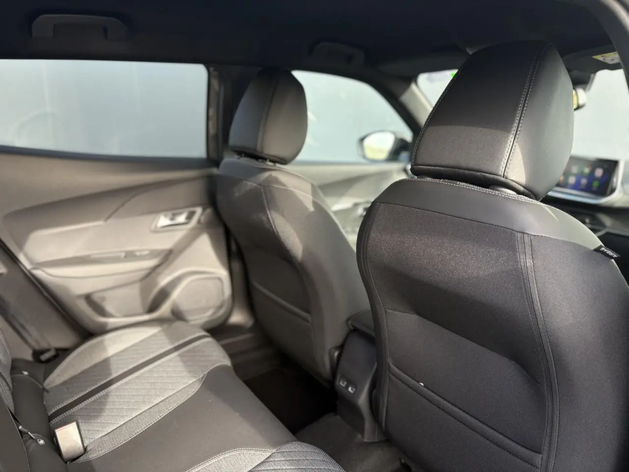 Vue intérieure arrière du Peugeot 2008 Hybrid 145 e-DSC6 Allure 2025, sièges tissu noir et gris, habitacle lumineux.