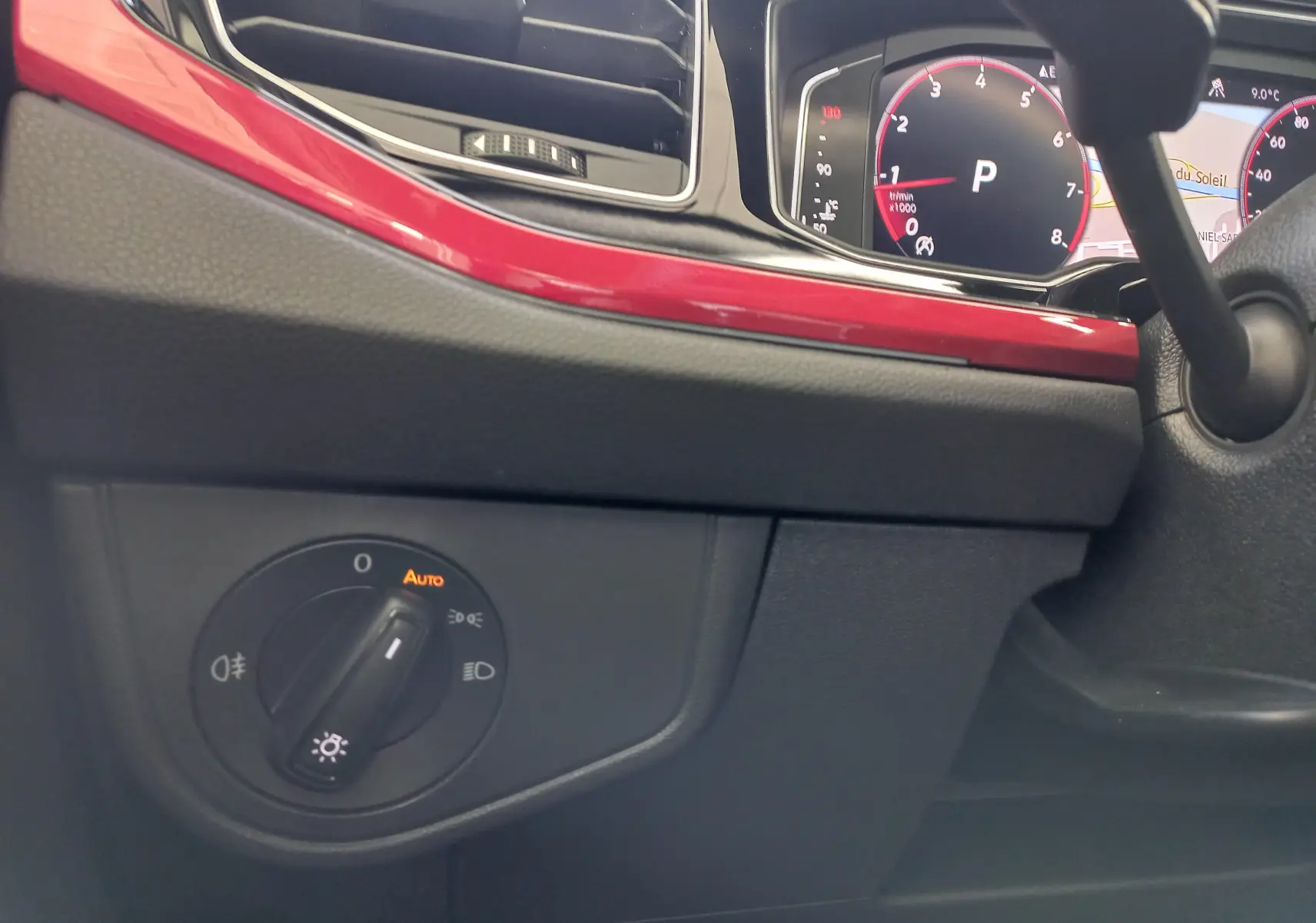 Gros plan sur le tableau de bord de la Volkswagen Polo 2024, avec bandeau rouge brillant et commandes d'éclairage.