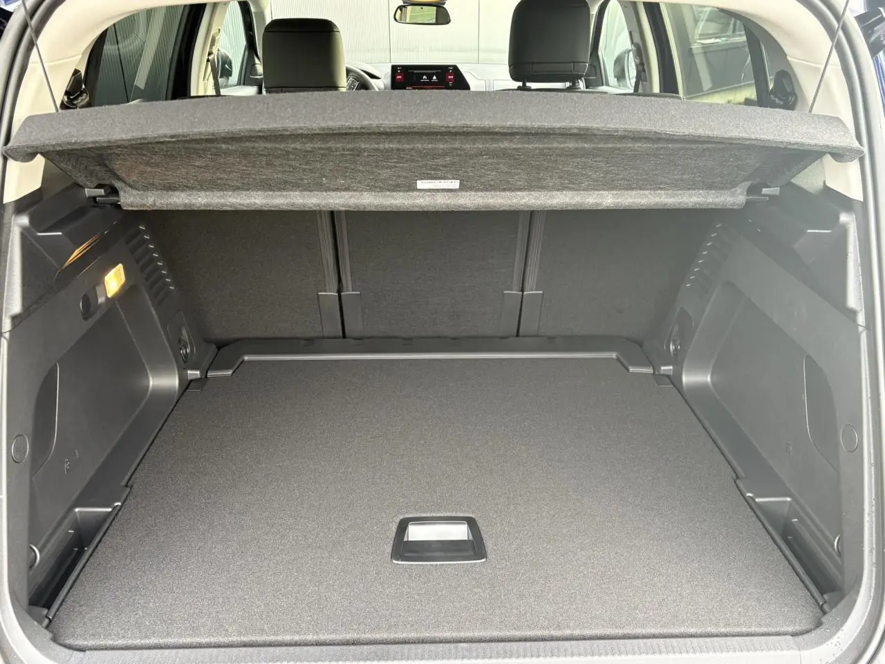 Coffre ouvert vu de l'arrière d'un Citroën C5 Aircross Bleu Eclipse avec cache-bagages et banquette arrière noire.