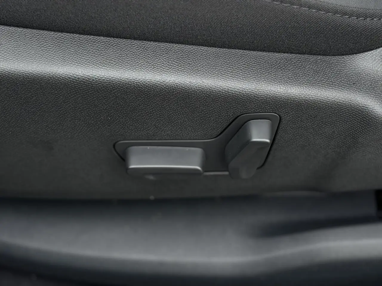 Gros plan sur les commandes électriques de réglage du siège avant noir du Citroën C5 Aircross Bleu Eclipse.